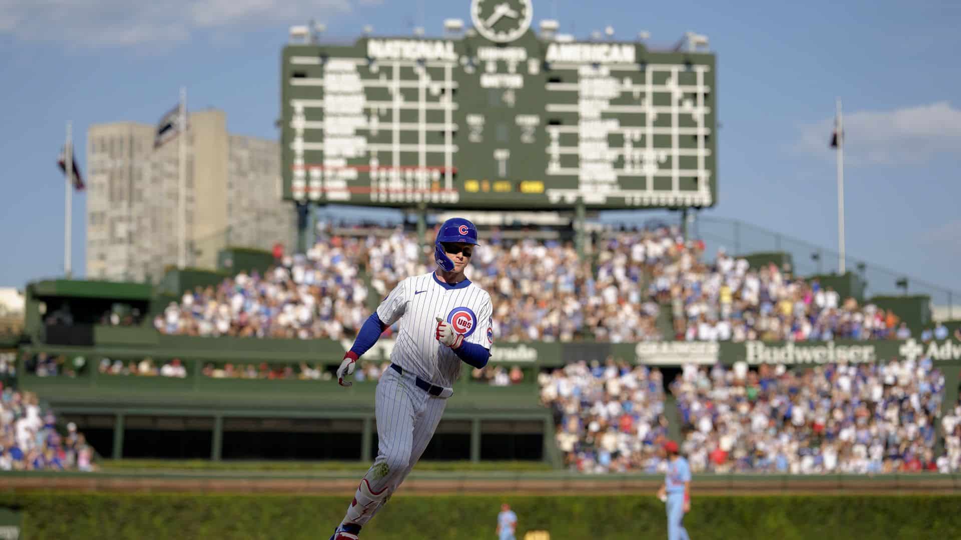 Wrigley Field, home of the Chicago Cubs, packed with fans on a sunny game day — the iconic hand-operated scoreboard visible in the background