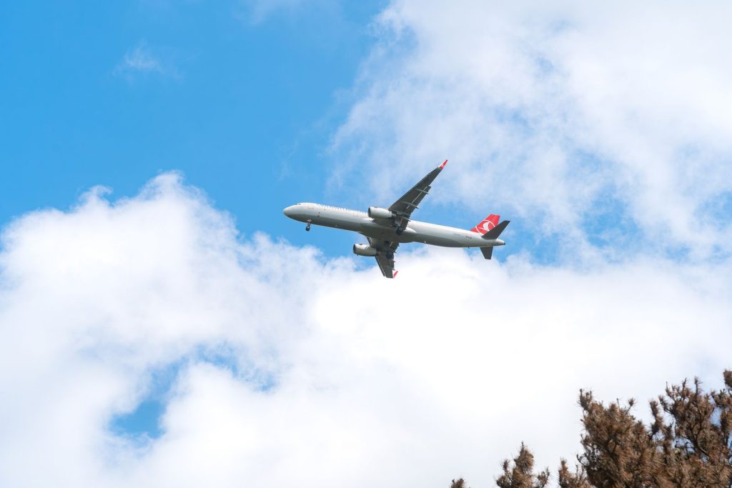Commercial airliner flying through a blue sky with clouds