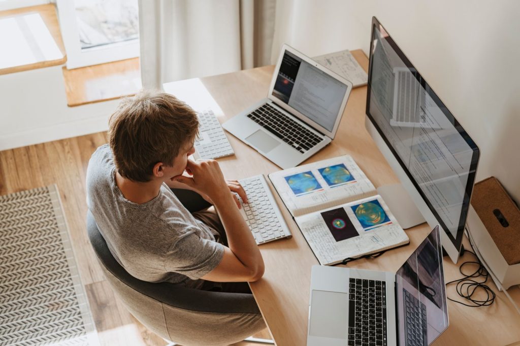 Engineer researching at a desk with a laptop, monitor and tablet