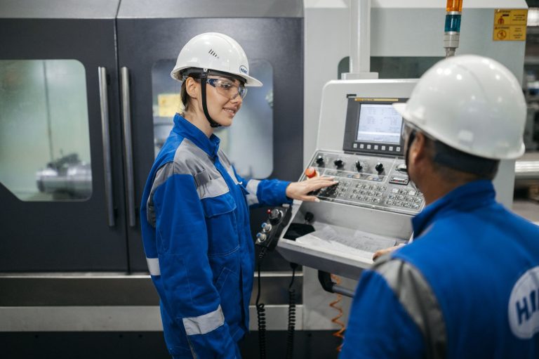 Two engineers in hard hats reviewing results at a machine control panel
