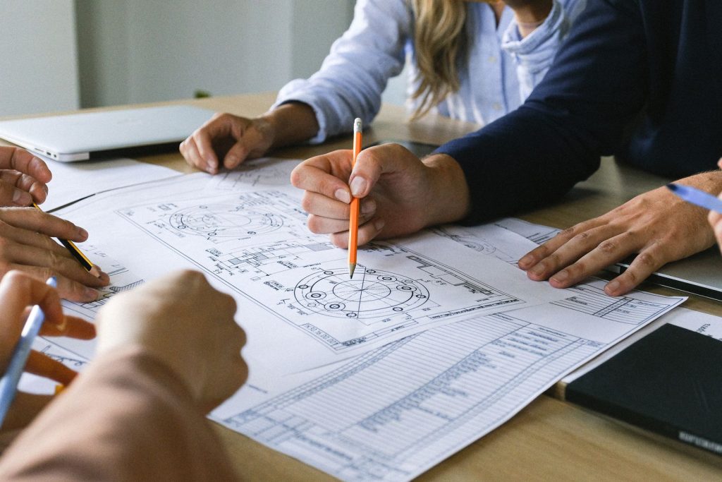 Engineering team marking up technical drawings on a table