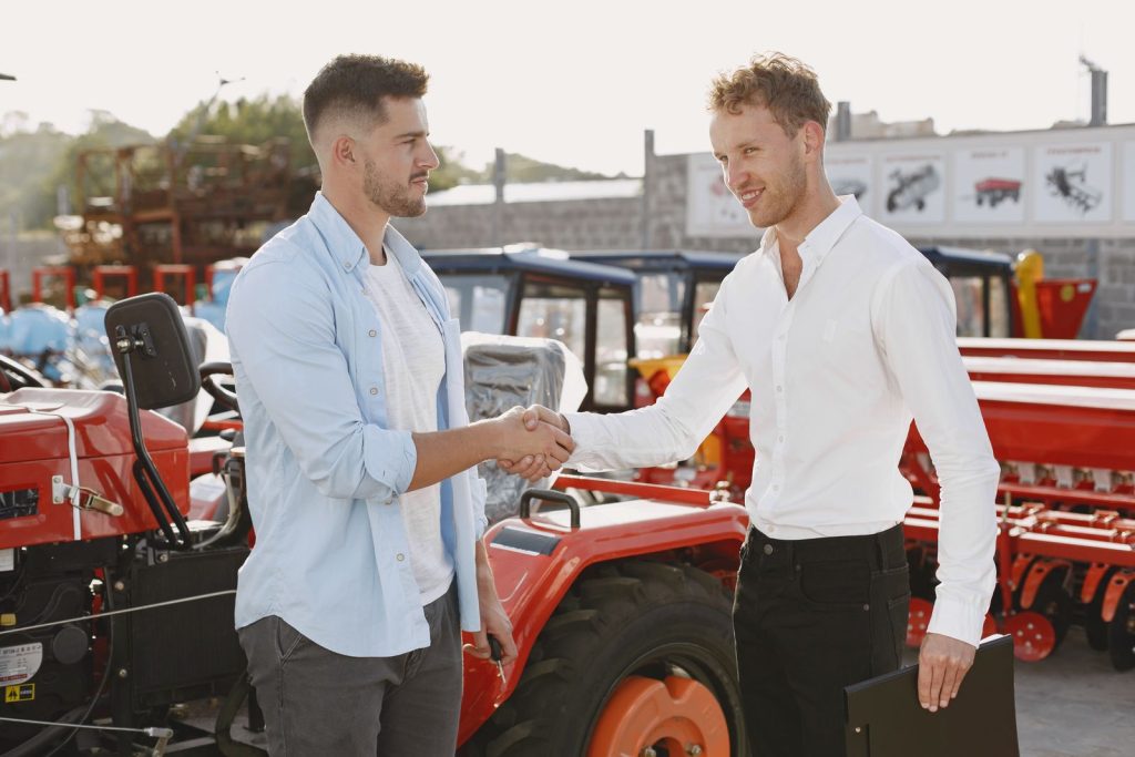 Two businessmen shaking hands next to industrial equipment