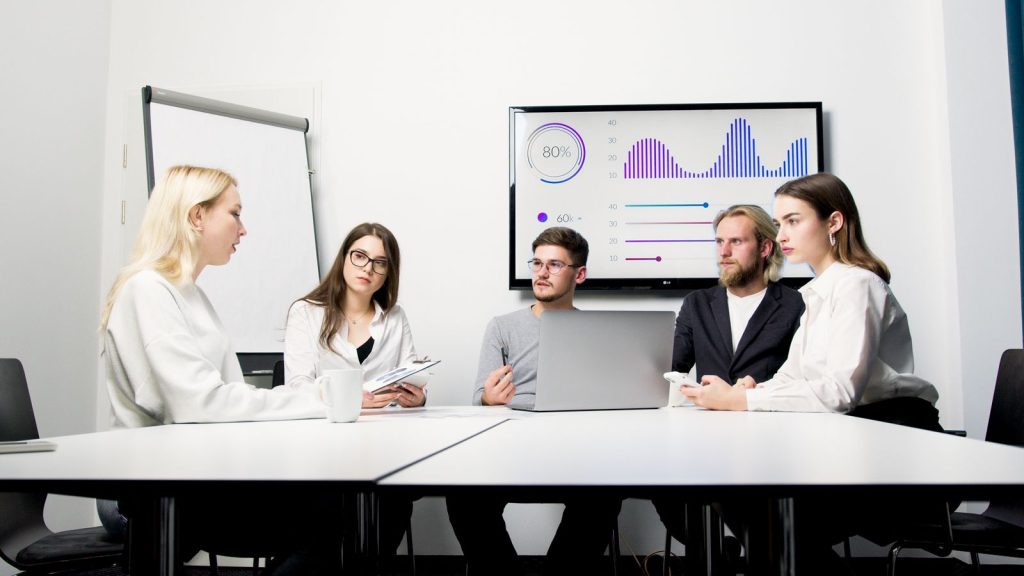Team meeting in front of a screen showing KPI charts