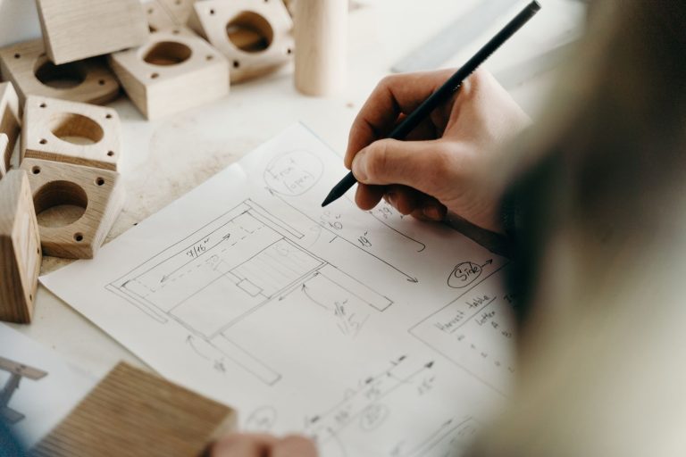 Engineer sketching a technical drawing next to machined parts