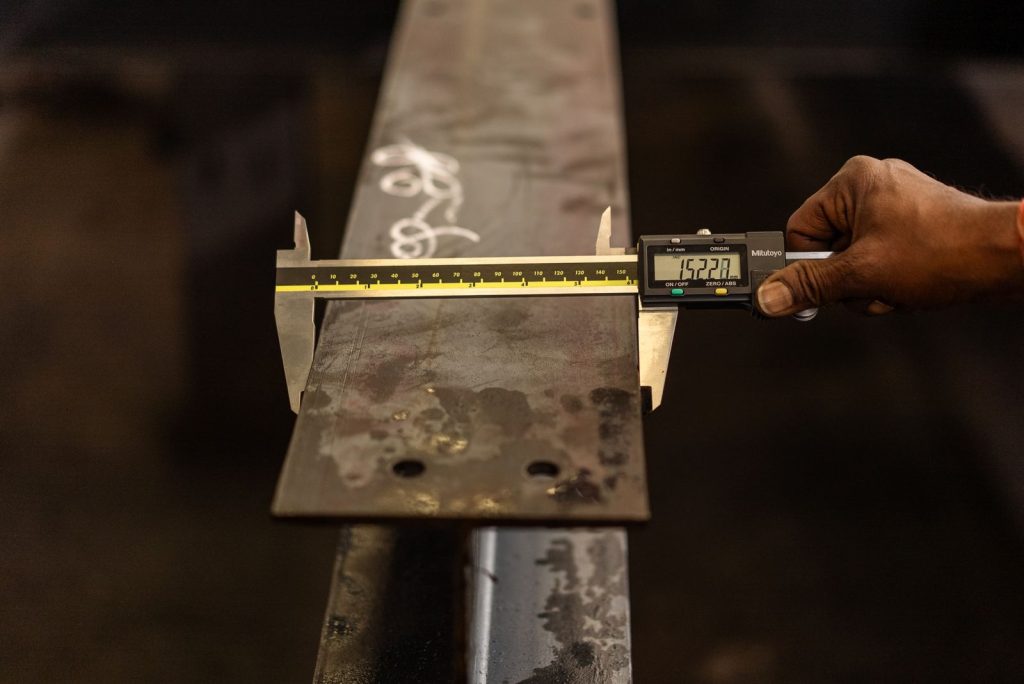 Inspector measuring a metal part with a digital caliper