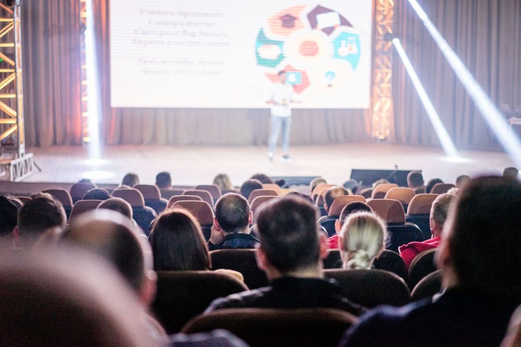 Speaker presenting on stage to a full conference audience