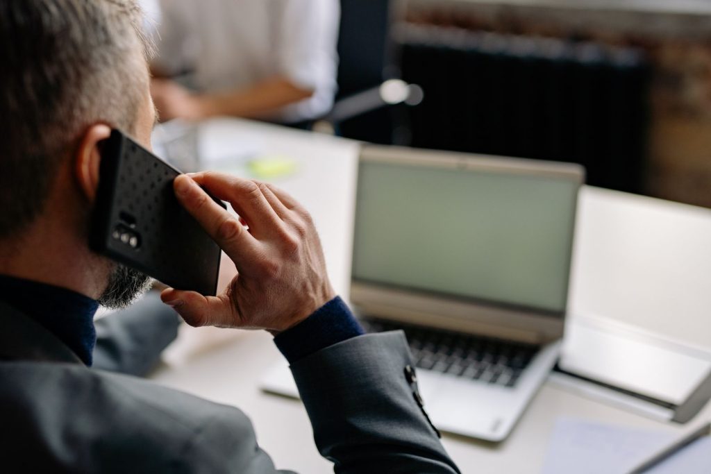 Sales rep making a follow-up phone call at a laptop